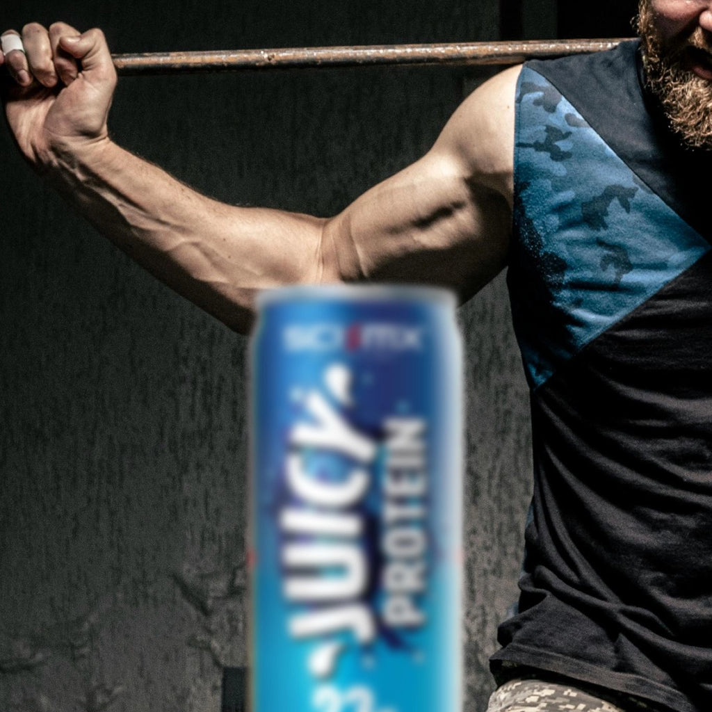 Person with muscular arms holding a barbell, with a can of Juicy Protein in the foreground.