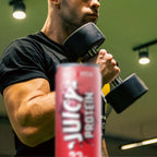 Person lifting dumbbells with a can of Juicy Protein in the foreground.