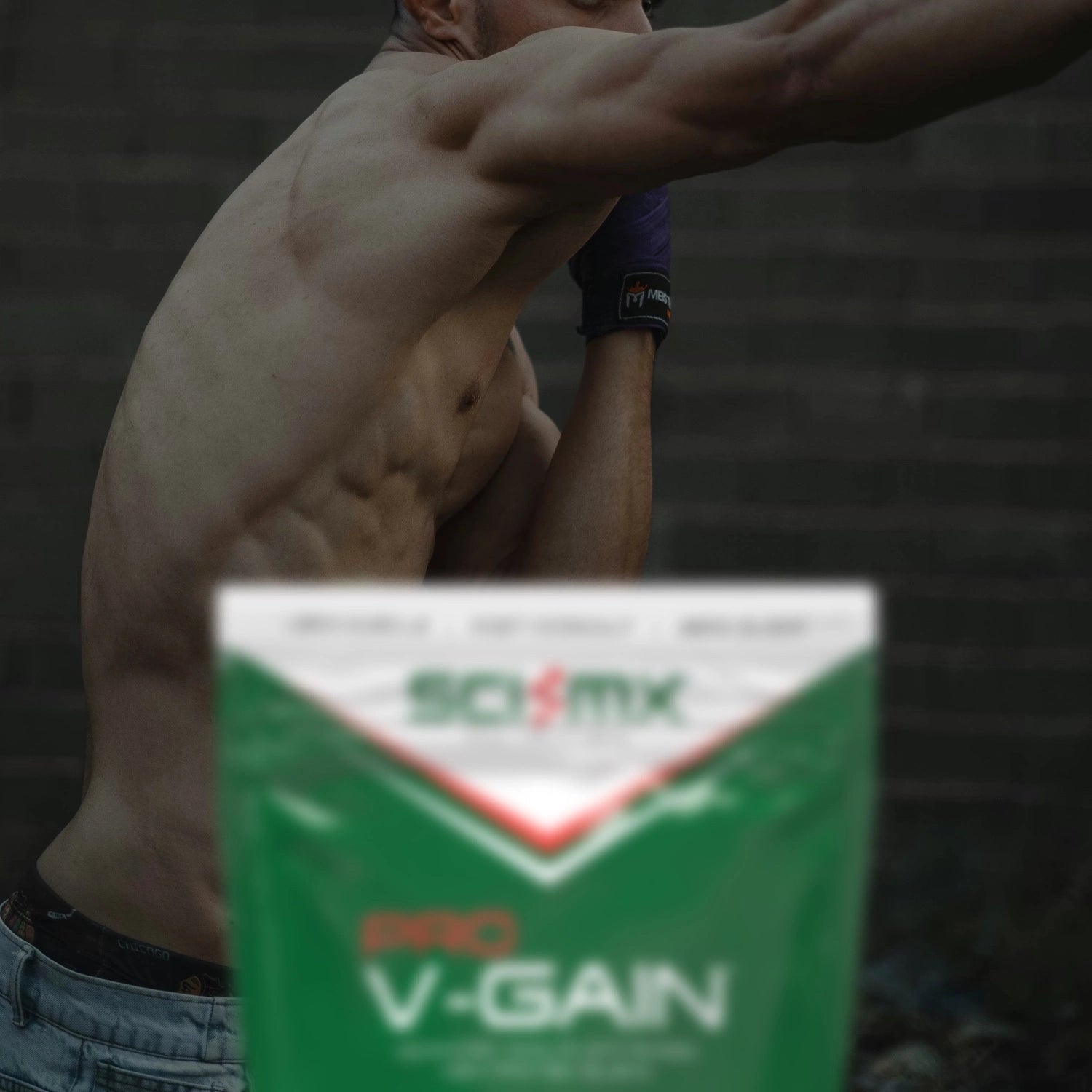 Man flexing muscles with a Pro 'V-Gain' supplement package in the foreground