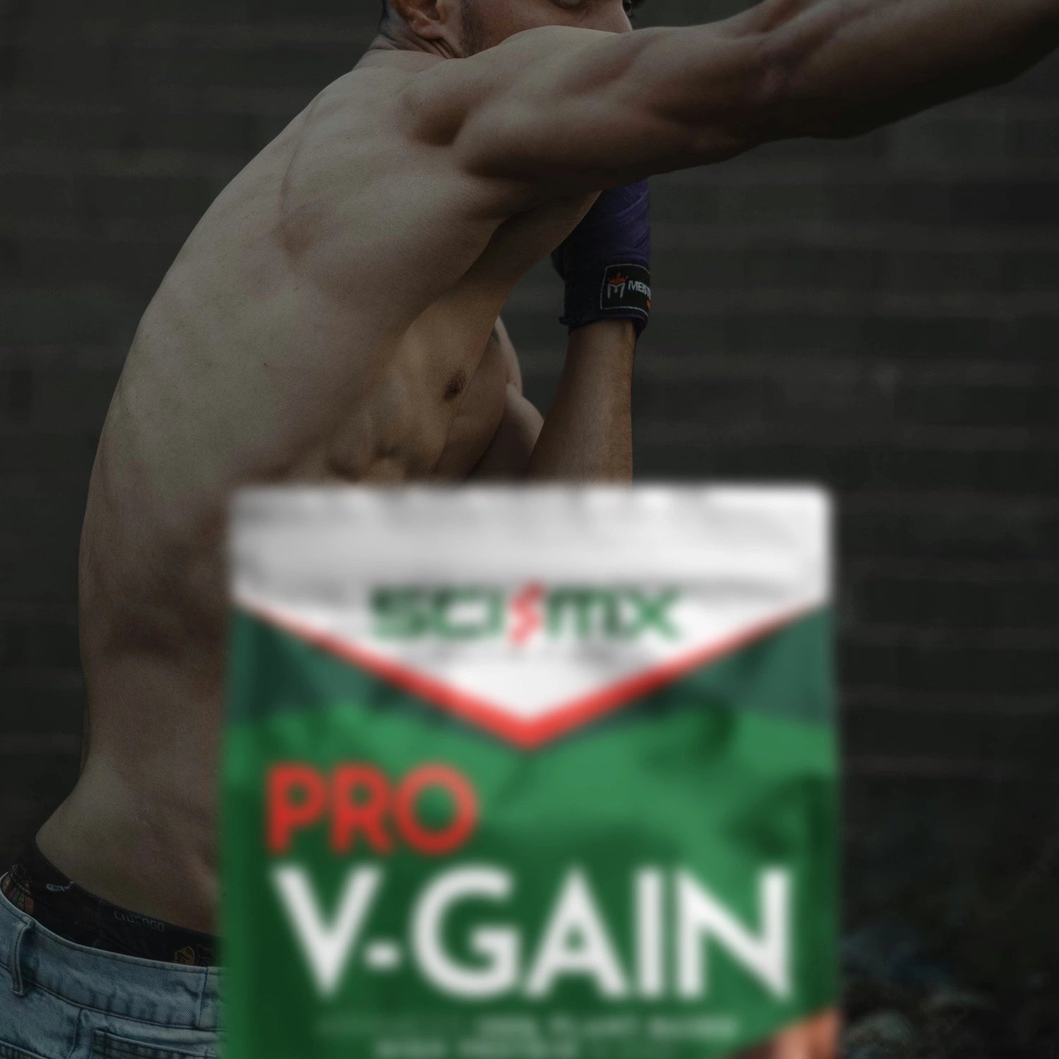 Person shadow boxing with a Sci-Mx Pro V-Gain supplement container in the foreground