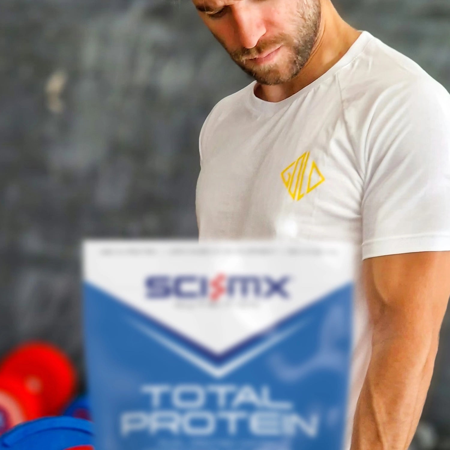 Man lifting weights with a Sci-Mx Total Protein container with a blurred background