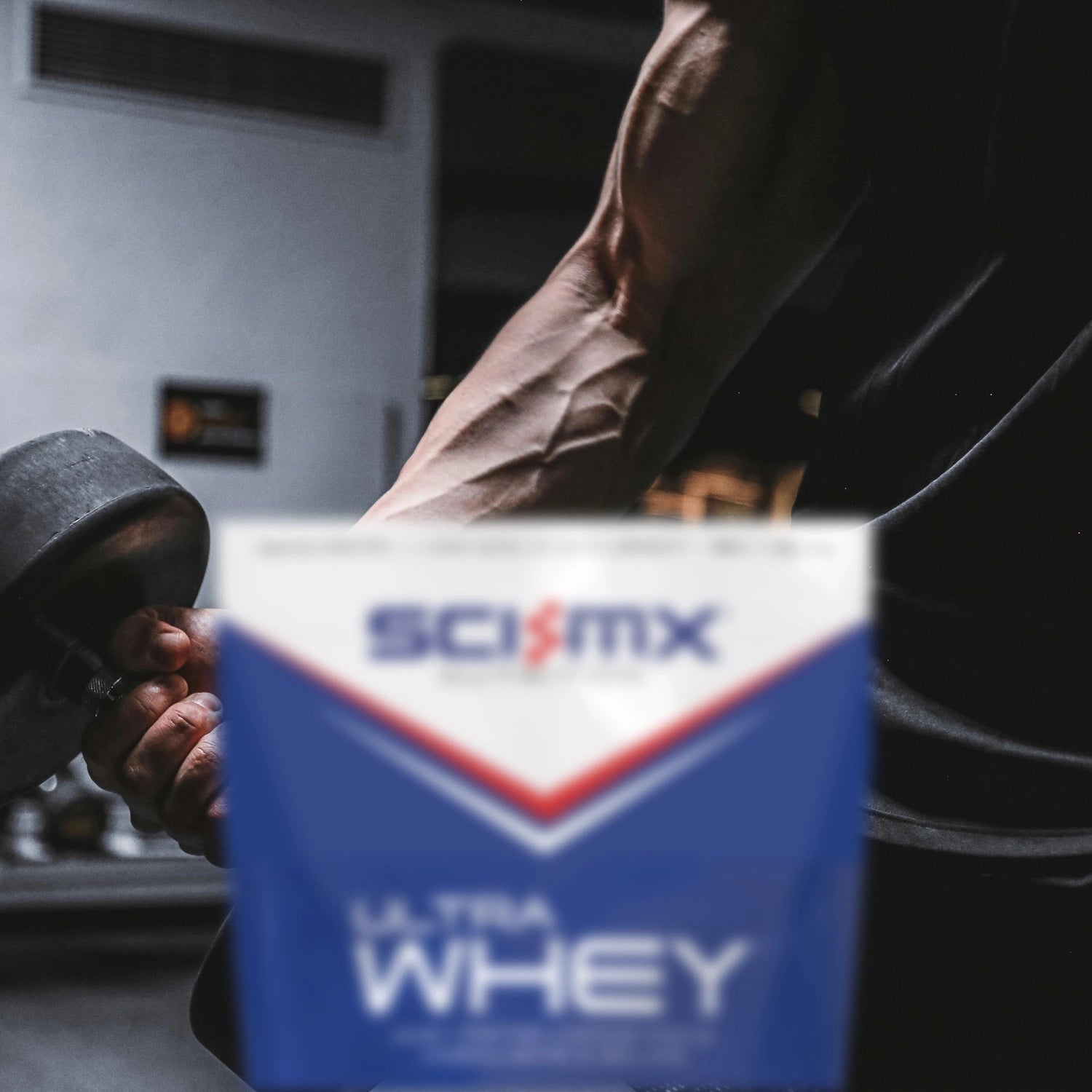 A man lifting a dumbbell with a container of Sci-Mx Ultra Whey protein powder in the foreground.