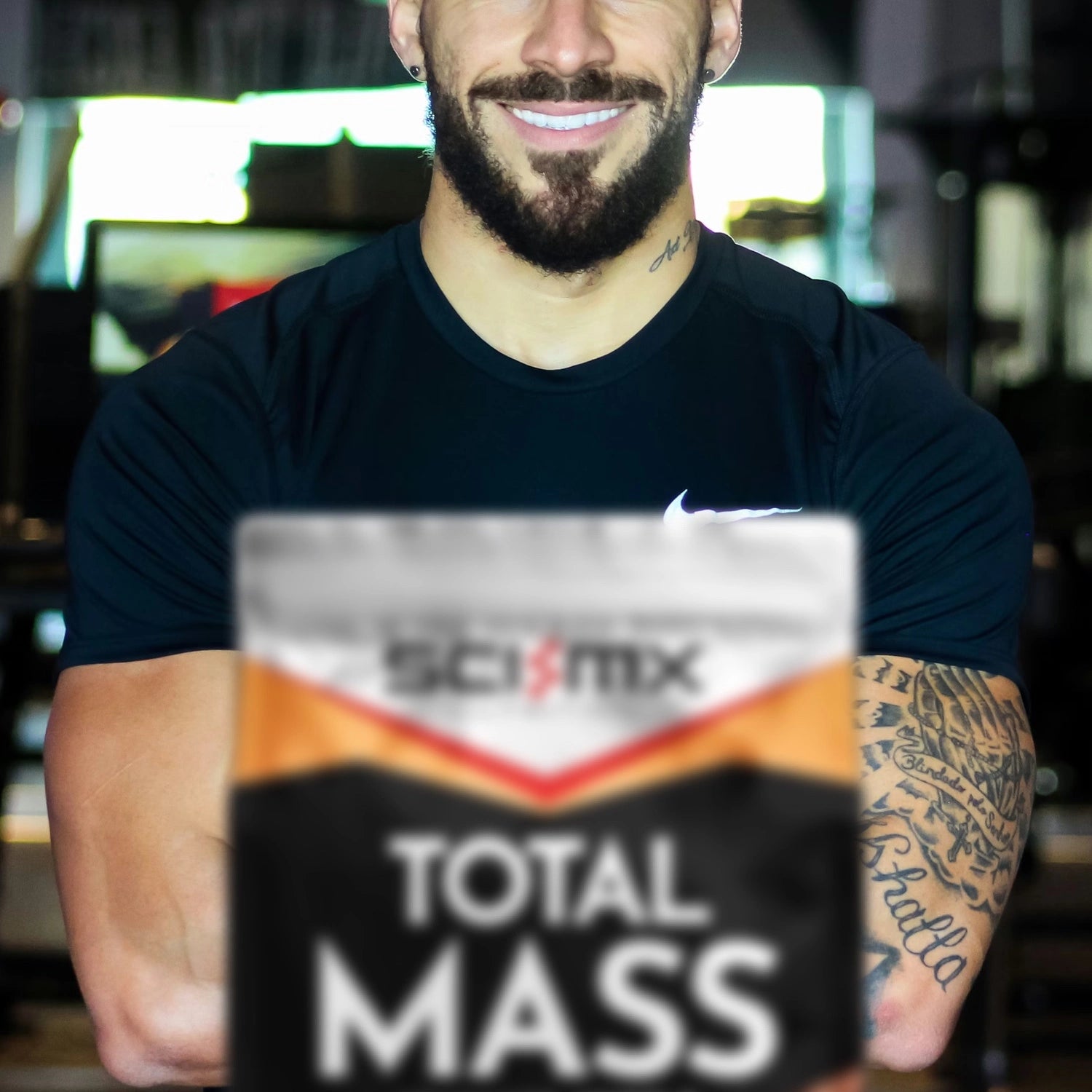 Muscular man standing in front of a package of Sci-Mx Total Mass supplement 
