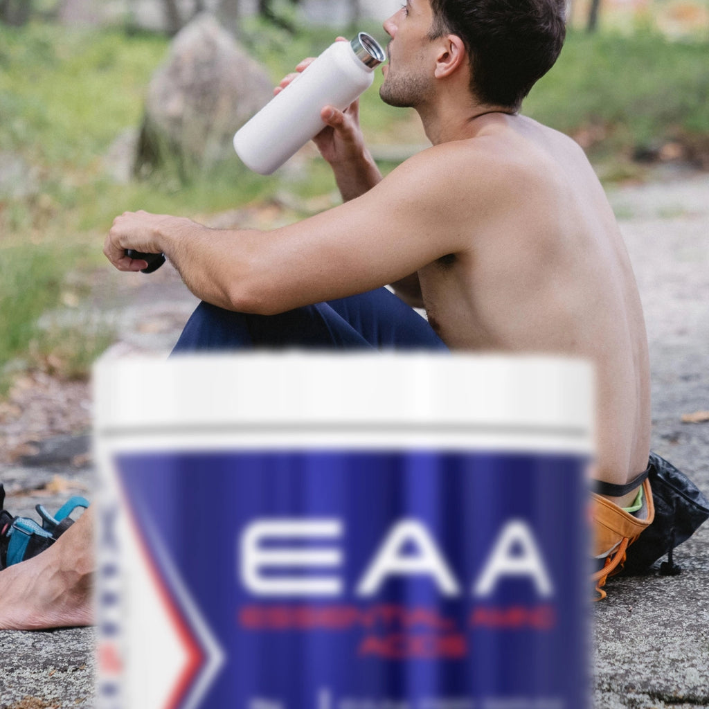 Man sitting outdoors drinking from a white bottle with a container of 'EAA' in the foreground.