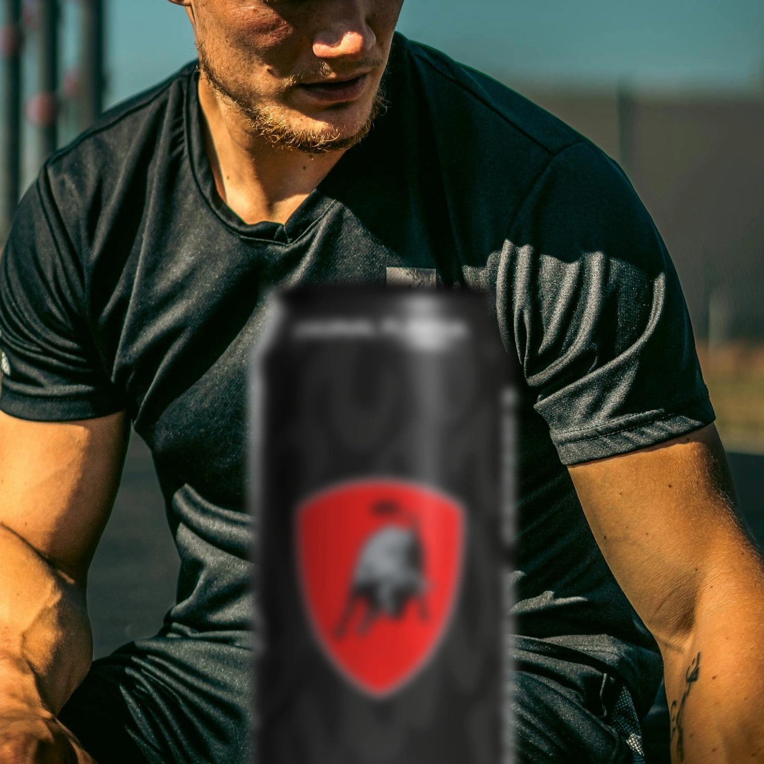 Man training outdoors with a can featuring the Lamborghini logo in the foreground.