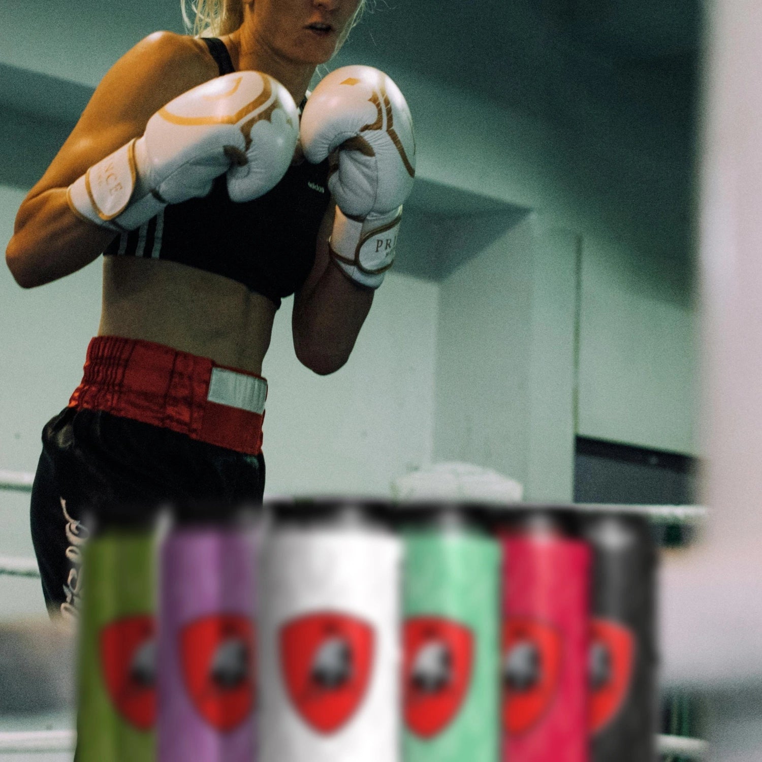 Woman training with boxing gloves with energy drinks in foreground