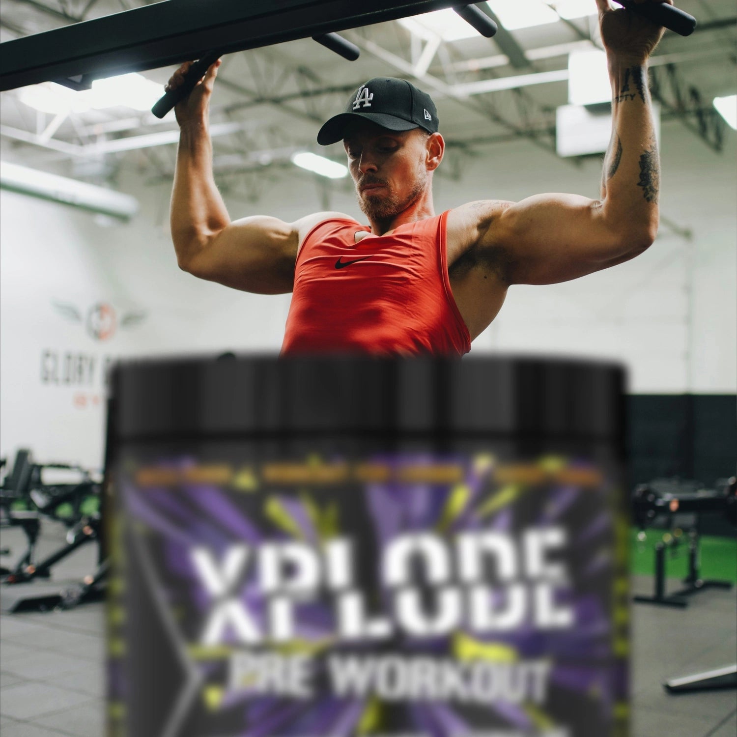 Person doing pull-ups in a gym with Explode Pre Workout in the foreground.