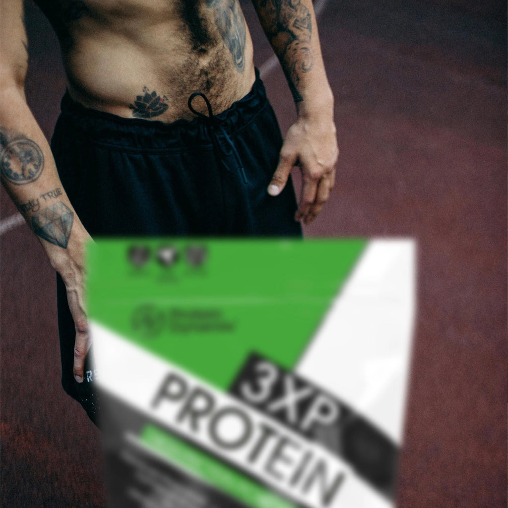 Person training wearing black shorts with a blurred 3XP Protein container in the foreground
