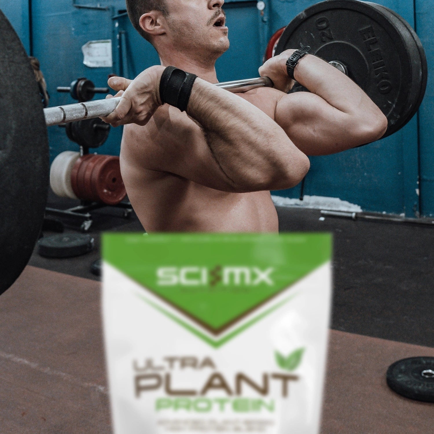 Person lifting weights with a Sci-Mx Ultra Plant Protein package in the foreground.