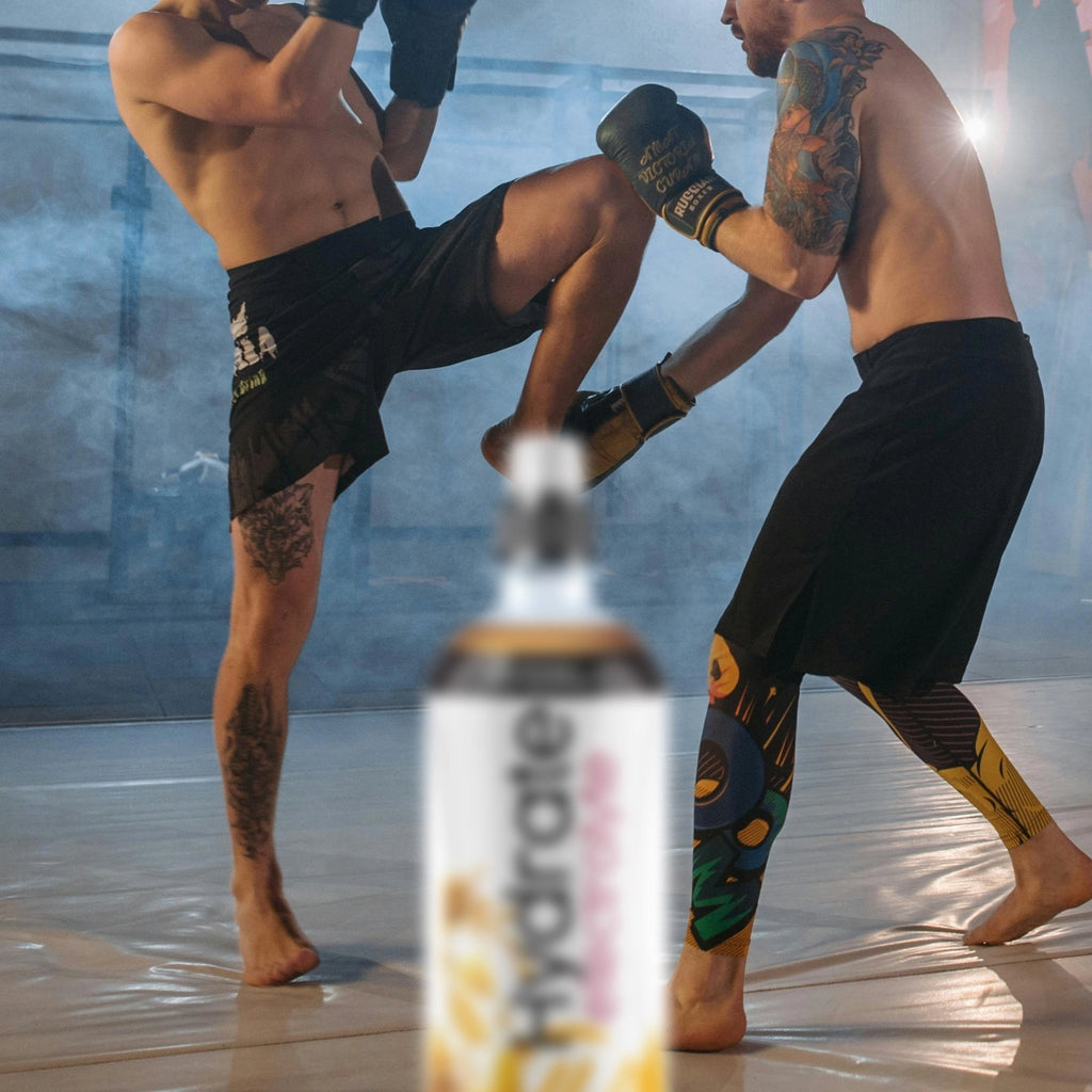 Two athletes are training in martial arts with a  Hydrate Electrolyte bottle in the foreground.