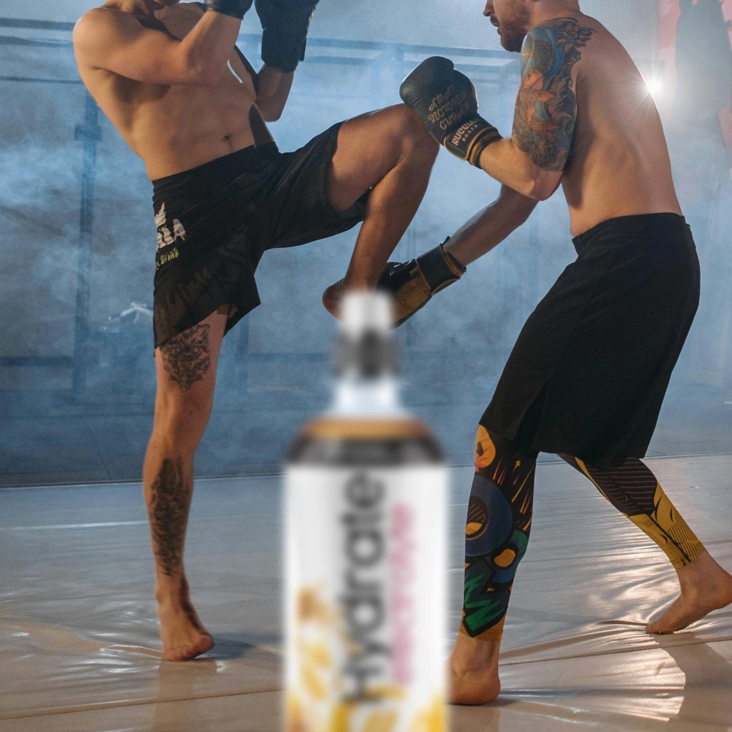 Two athletes are training in martial arts with a  Hydrate Electrolyte bottle in the foreground.