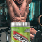 Man in a gym setting with a container of Whey Protein Isolate in the foreground.