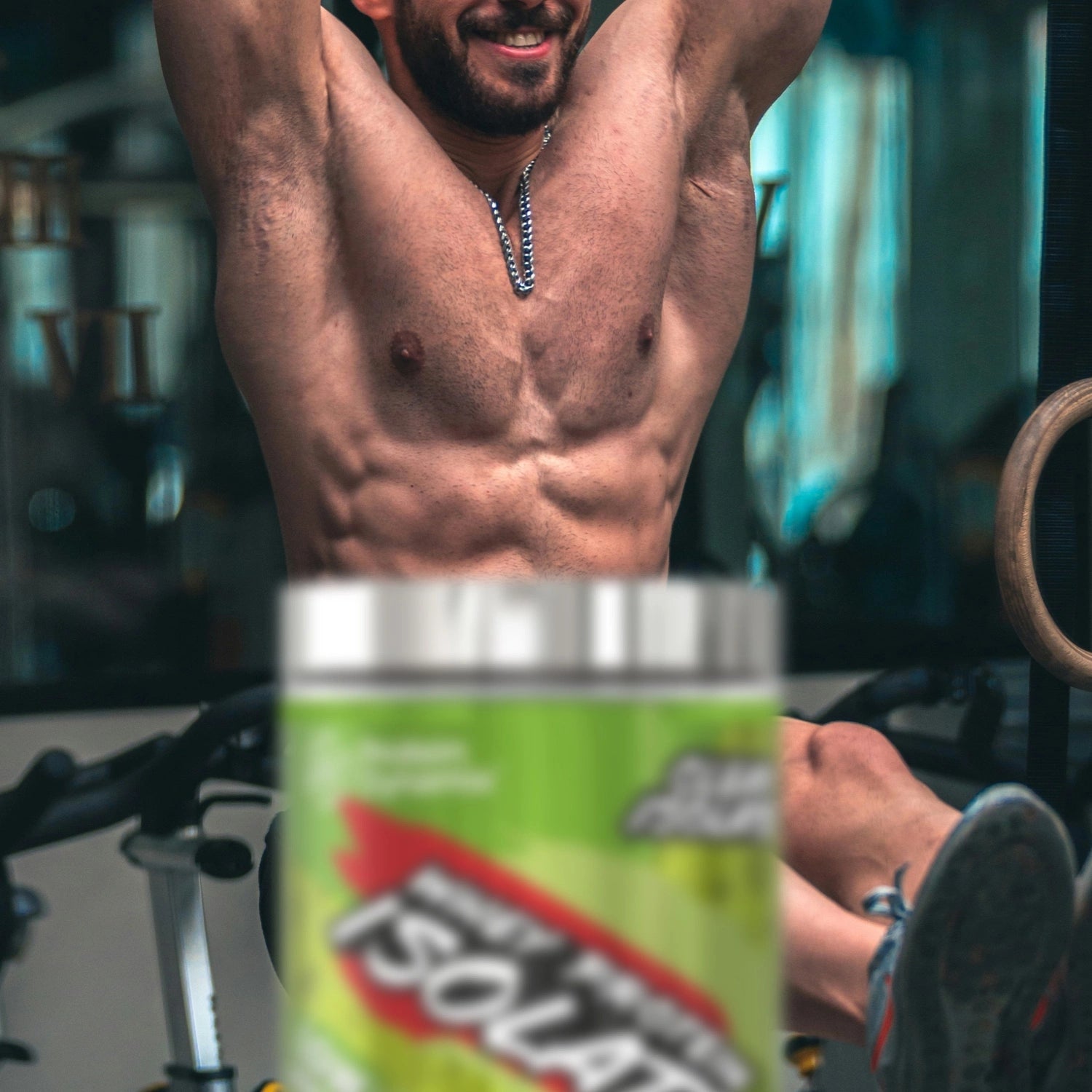 Man in a gym setting with a container of Whey Protein Isolate in the foreground.