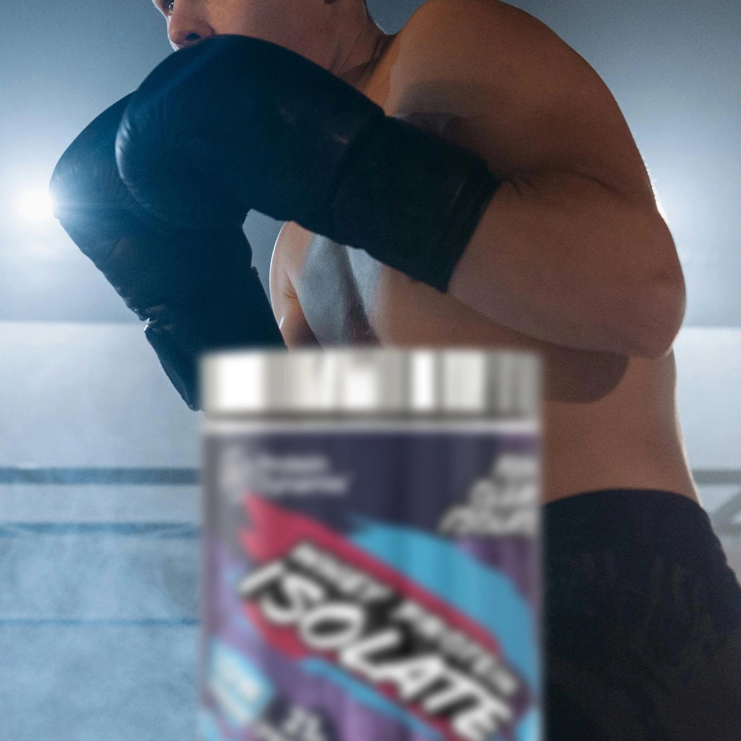 Person wearing boxing gloves with a Whey Protein Isolate container in the foreground